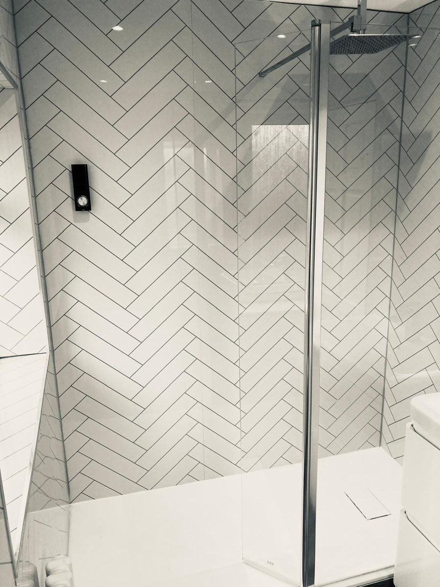 White herringbone tiled walk-in shower with black valve